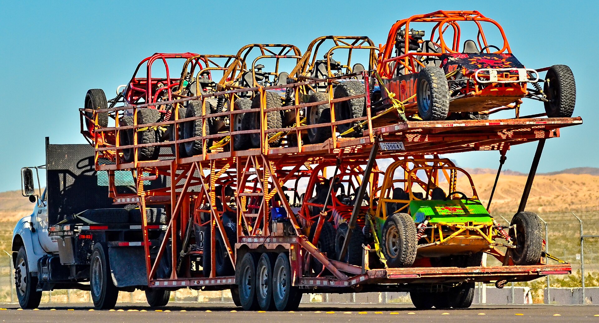 a truck carrying several off-road vehicles on a trailer