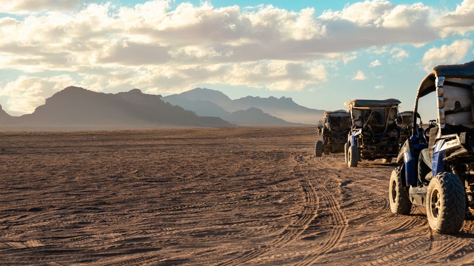 ATVs parked on a dirt track with mountains in the background
