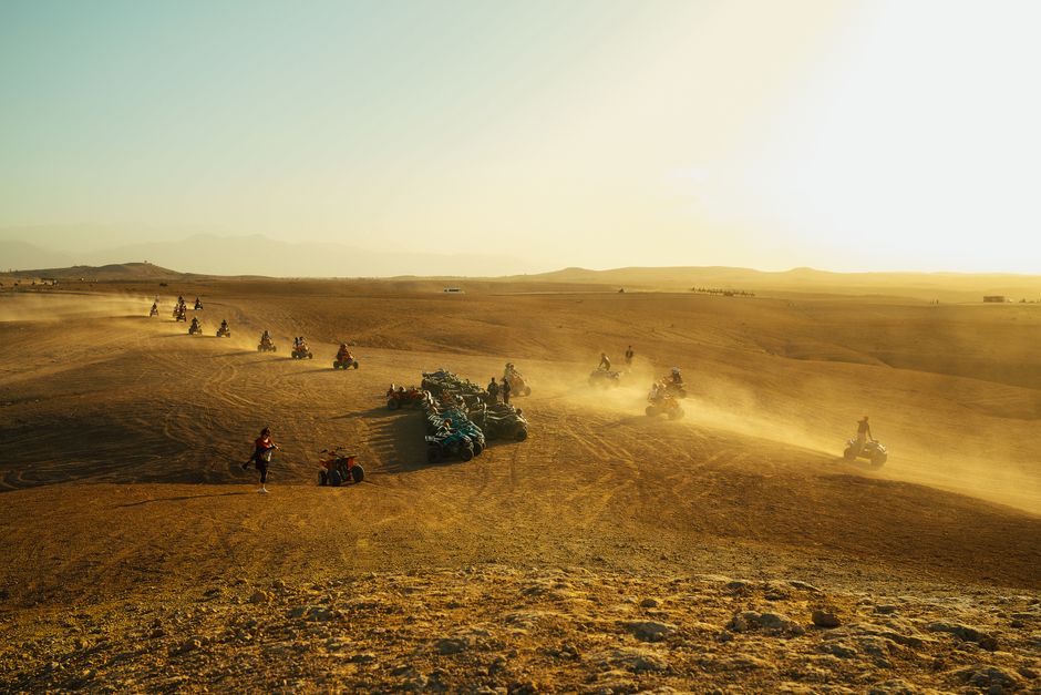 ATVs driving on a desert trail, kicking up dust