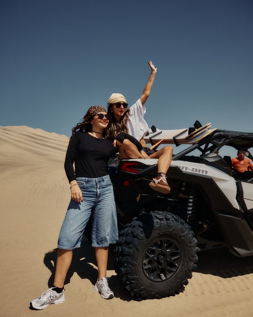 Two women standing and sitting on an ATV in the desert