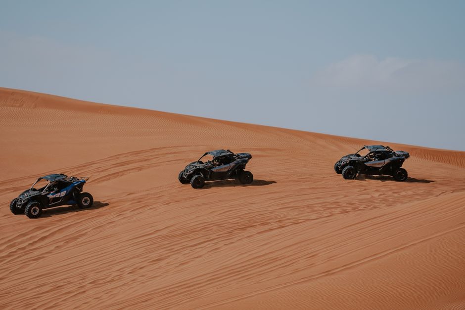 Three desert buggies racing on sand dunes