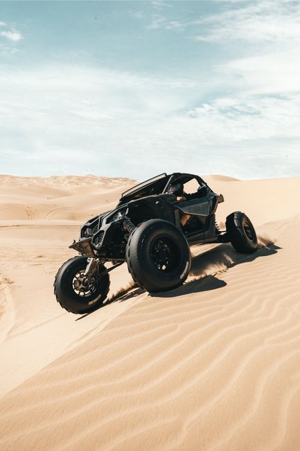 A black desert buggy driving on sand dunes