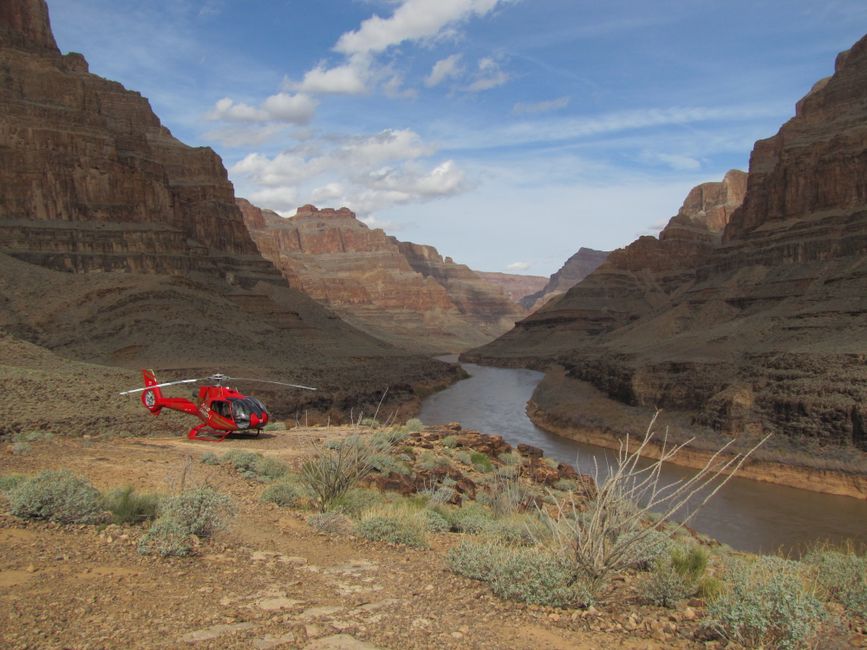 Red helicopter on a cliff overlooking a river in a canyon