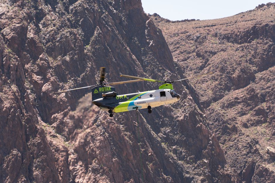 A helicopter with 'GRAND CANYON HELICOPTERS' and 'N266RH' on its side flying over a canyon