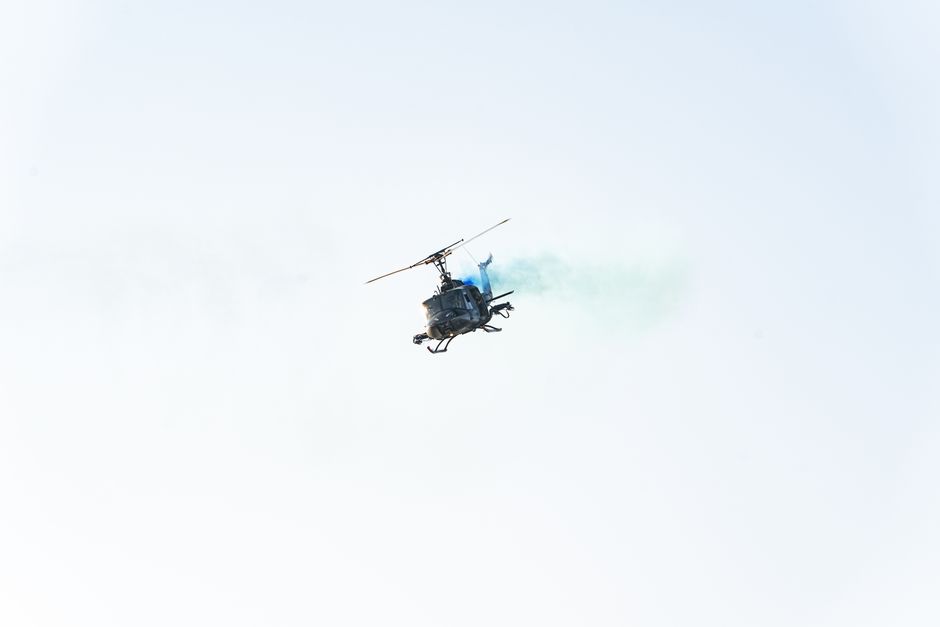 A helicopter flying in the sky with smoke behind it