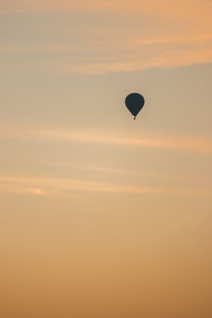 a dark hot air balloon in a pastel orange sky