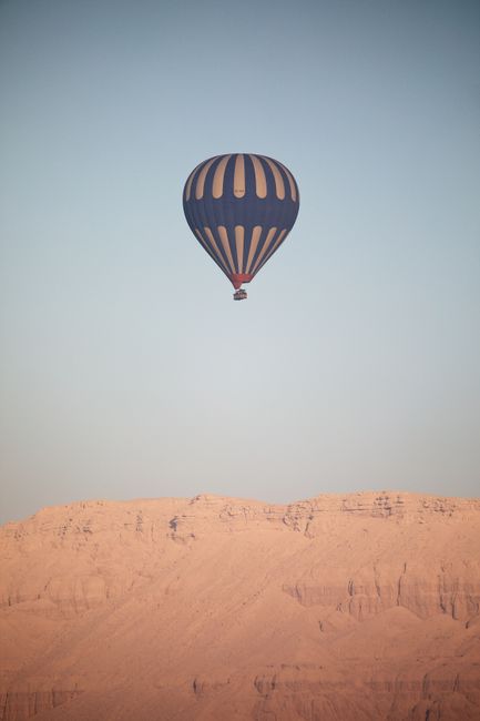 A hot air balloon flying over a desert canyon