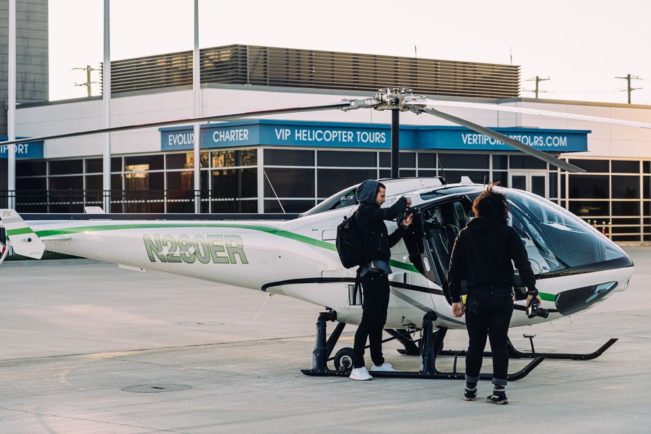 Two people boarding a white and green helicopter on a helipad