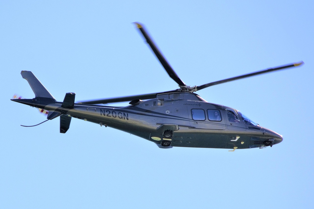 A dark gray helicopter with N20GN on the side flying in a blue sky