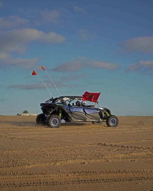 Off-road UTV with red flags driving on sand