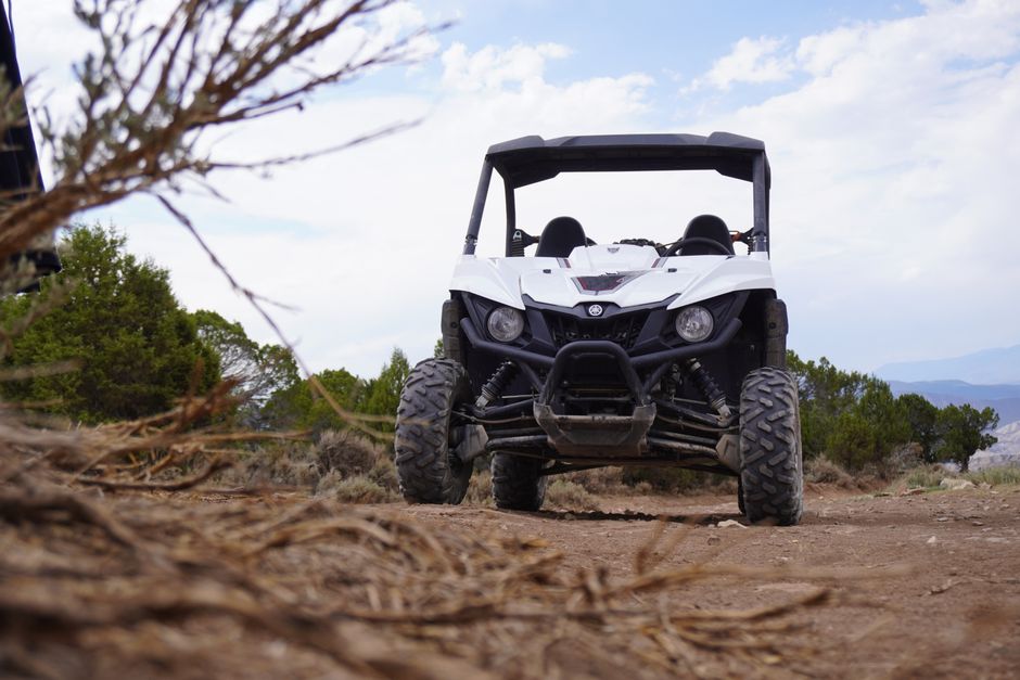 A white UTV on a dirt road with trees and mountains in the background