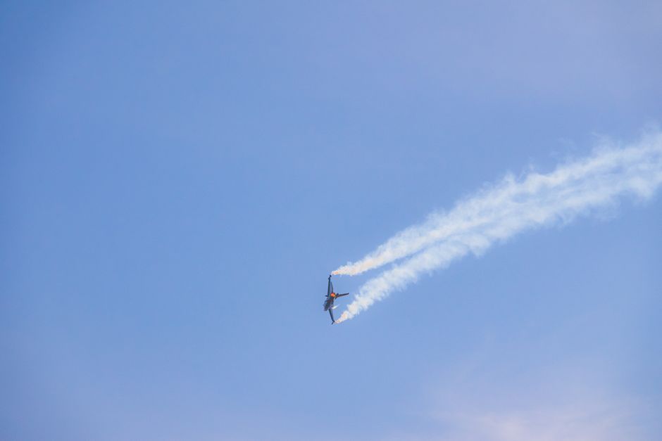 a small airplane flying in a blue sky with white smoke trails