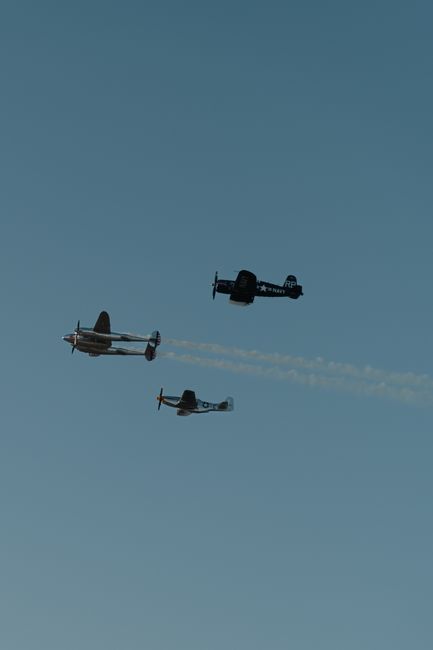 three small planes flying in formation against a blue sky