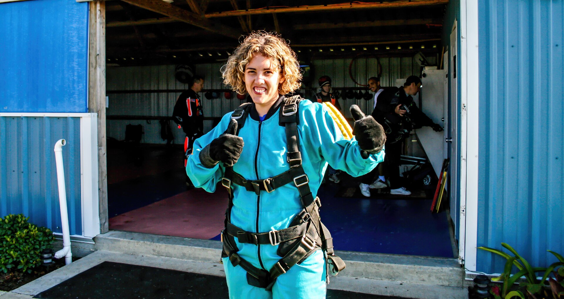 Woman in skydiving gear giving thumbs up