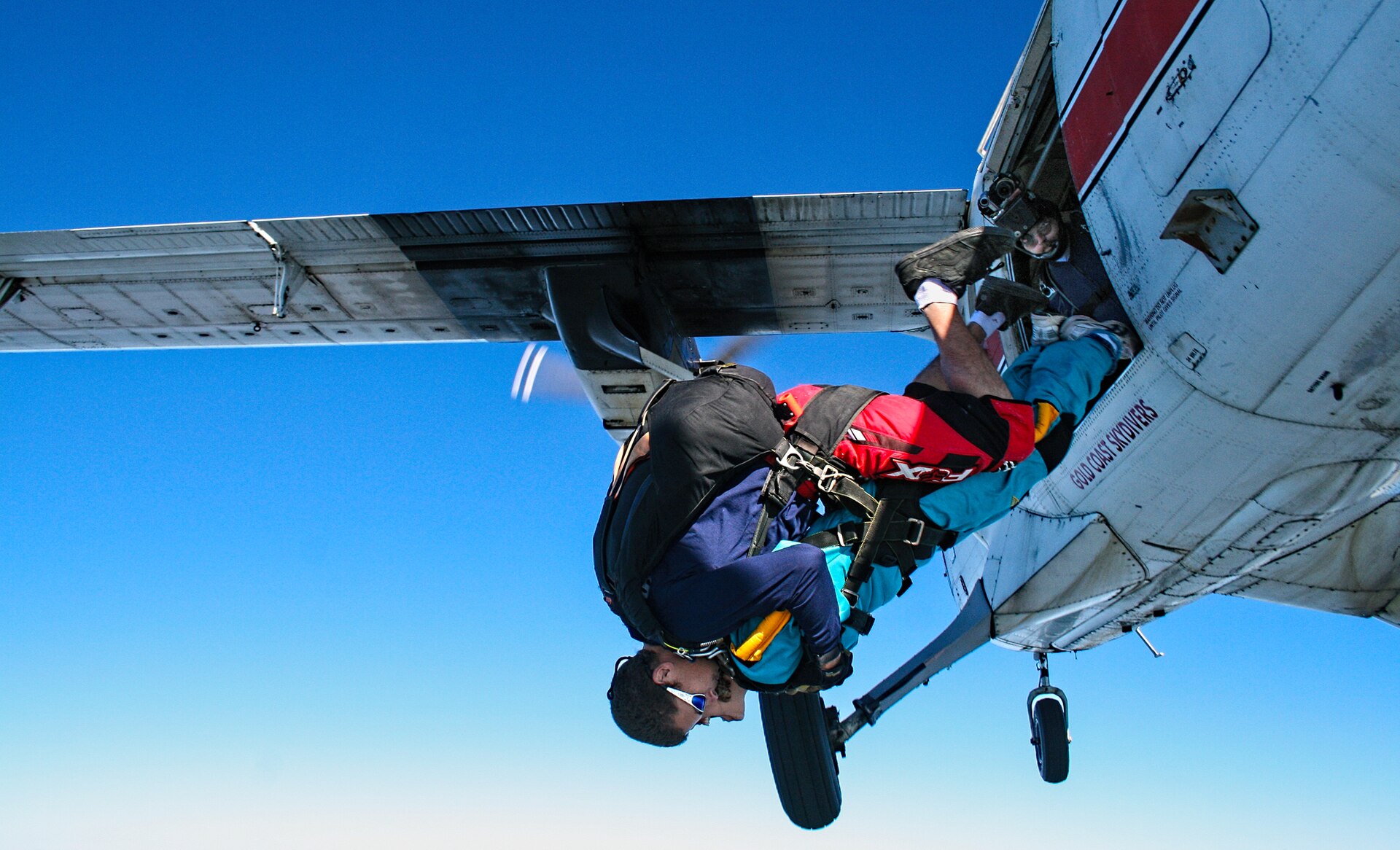Two people exiting an airplane door while skydiving