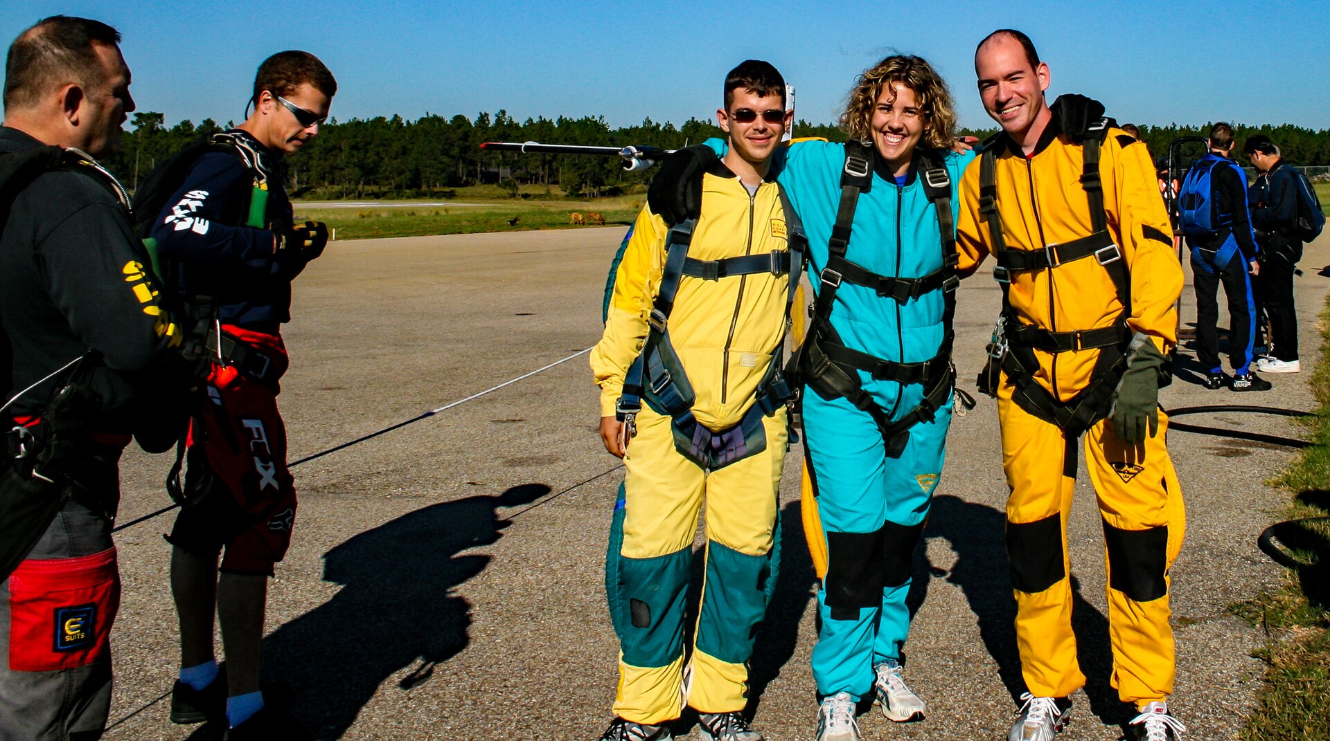 People in skydiving gear standing on a runway