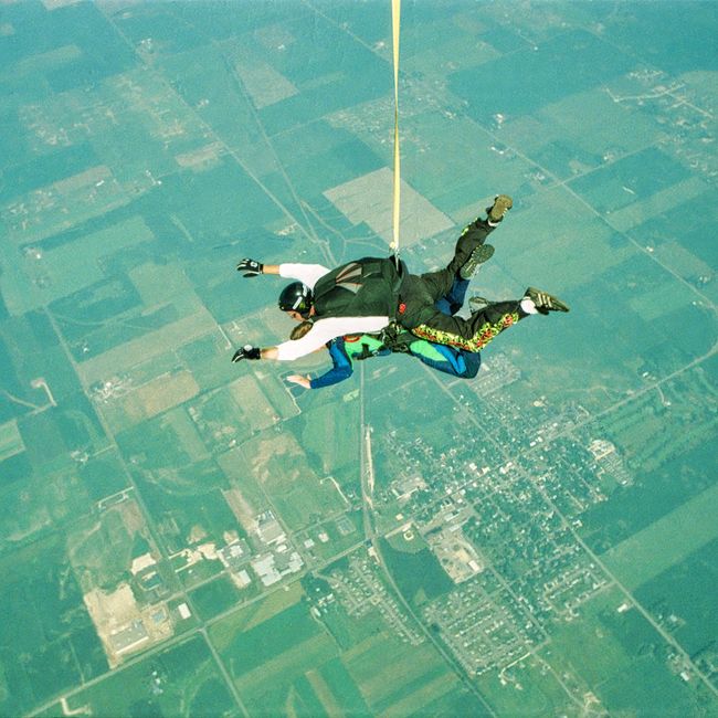 Two people skydiving over a patchwork landscape